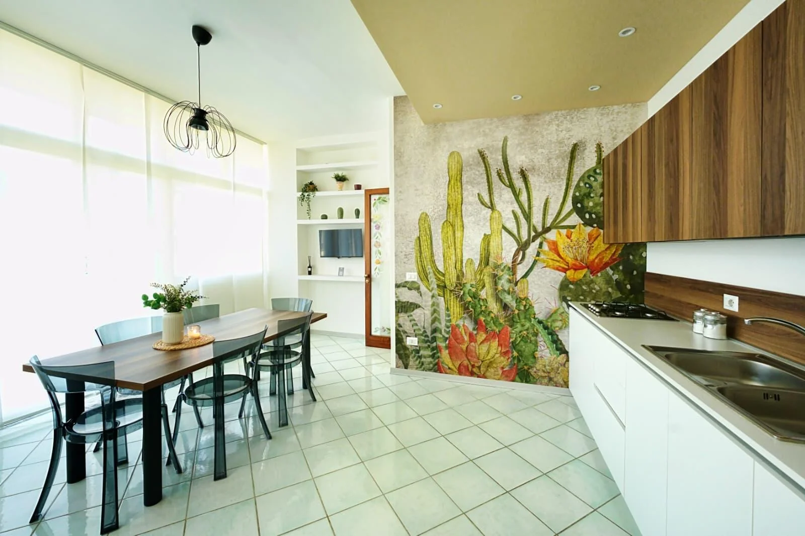 Sunlit dining area and kitchen at Casalicia, with a colorful cactus mural